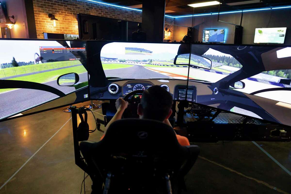Mike McLennan, manager of Emergent VR Encounter, competes with colleague, Joel Chan, during a virtual realty car race, Tuesday, March 30, 2021, in Spring. The facility opened in 2018 and offers a variety of virtual reality experiences such as golfing, racing and more.