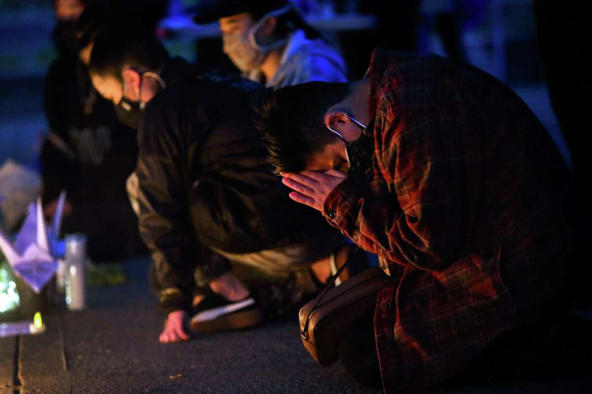 Kiara Konishi (they/them) of Oakland prays in front of an altar as hundreds gather for the "from the Bay to Atlanta: on our minds, in our hearts" event at Madison Park on Tuesday, March 23, 2021, in Oakland, Calif. The gathering was held in memory of eight victims, six of whom were Asian women, who were killed one week ago in Atlanta during a mass shooting.