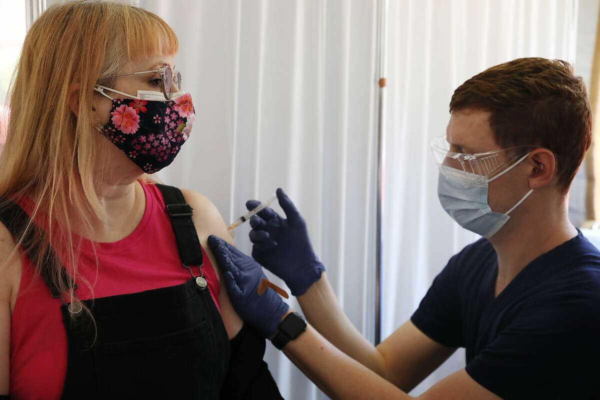 Gabrielle Arroyo (left) receives a Moderna COVID-19 shot from William Wohlfeiler at the Southeast Health Center in San Francisco. California will retire its color-coded pandemic blueprint on June 15 and allow almost all sectors of the economyto reopen at or near full capacity, state officials said Tuesday.