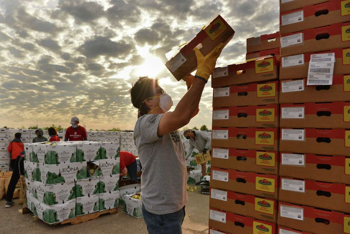 Juan Carlos Gonzalez stacks boxes of tomatoes during a San Antonio Food Bank mega distribution Friday morning at Brooks. Broadway Bank sponsored the event and donated $50,000.