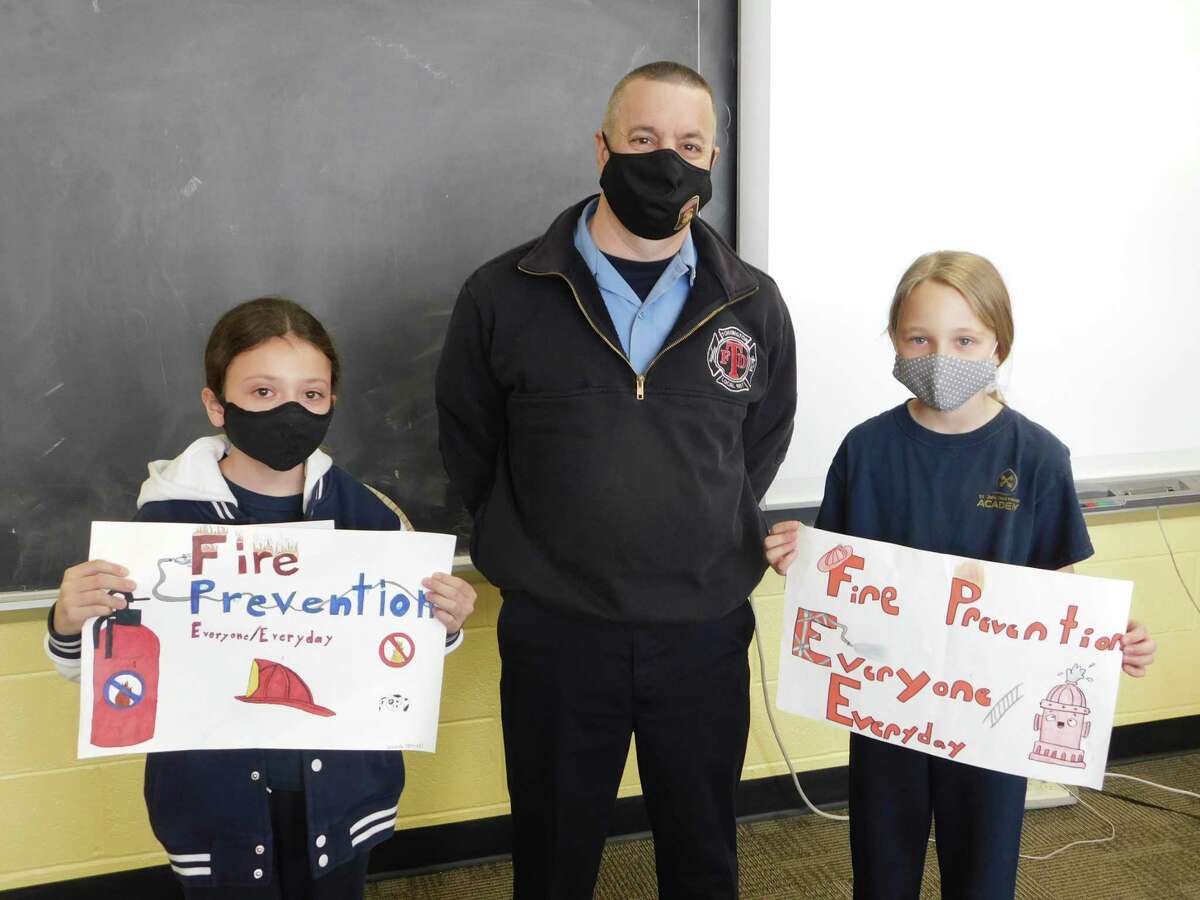 Jarred Howe, Torrington deputy fire marshal, stands with Isabella O’Brien, left, and Alexandra Mazzarelli, fifth-grade students at St. John Paul the Great Academy, winners of the 2021 fire prevention poster contest.