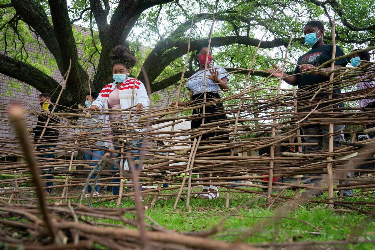 Community members (LtoR) Jaliya Josephine, Shalom Emedi and Nathan Chikala weave together branches to make a giant nest in front of Westbury United Methodist Church on Sunday, March 28, 2021, in Houston. The nest is designed to be reminiscent of a tomb, and it will sit in front of the church during Holy Week. On Easter, community members will fill the nest with flowers.
