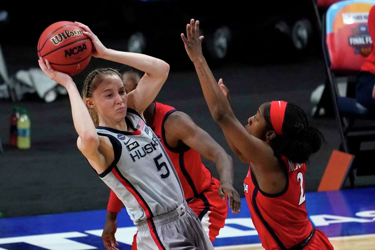 Connecticut guard Paige Bueckers (5) passes over Arizona guard Aari McDonald (2) during the first half of a women's Final Four NCAA college basketball tournament semifinal game Friday, April 2, 2021, at the Alamodome in San Antonio. (AP Photo/Eric Gay)