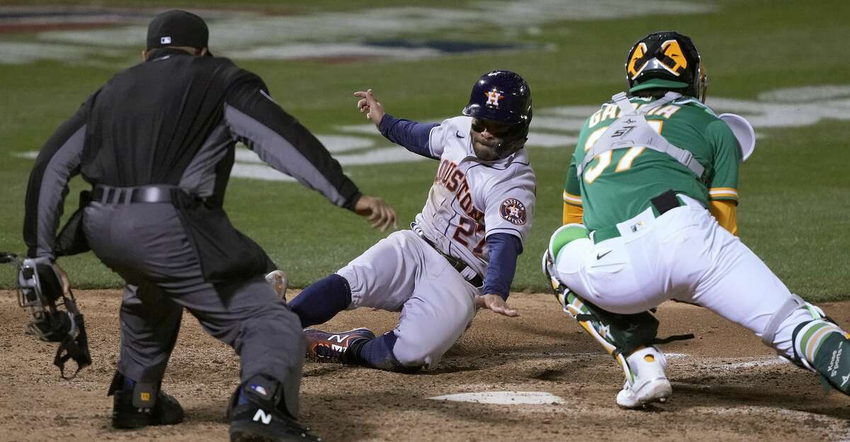 Houston Astros' Jose Altuve (27) slides into home plate to score a run past Oakland Athletics catcher Aramis Garcia (37) during the seventh inning of a baseball game Friday, April 2, 2021, in Oakland, Calif. (AP Photo/Tony Avelar)