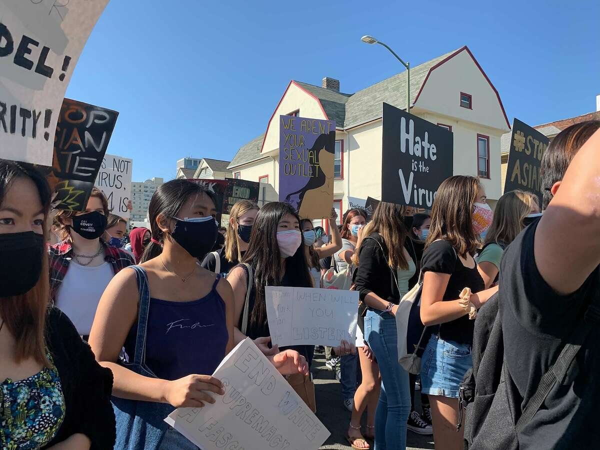 Approximately 200 marchers, most of them young, hold signs in support of the Asian American community during a youth-led rally through Oakland.