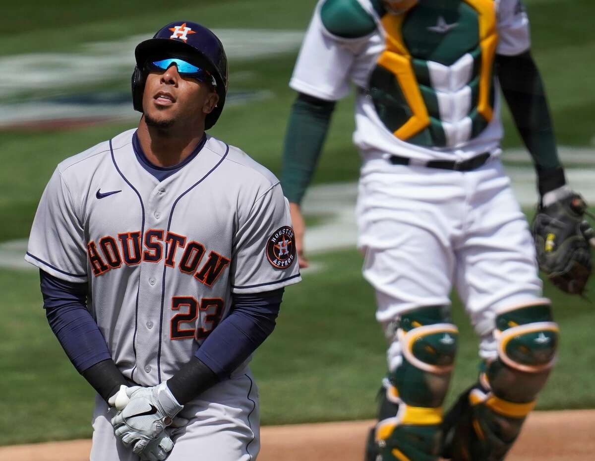 Houston Astros' Michael Brantley, left, reacts after being hit by a pitch in front of Oakland Athletics catcher Aramis Garcia during the first inning of a baseball game in Oakland, Calif., Saturday, April 3, 2021. (AP Photo/Jeff Chiu)