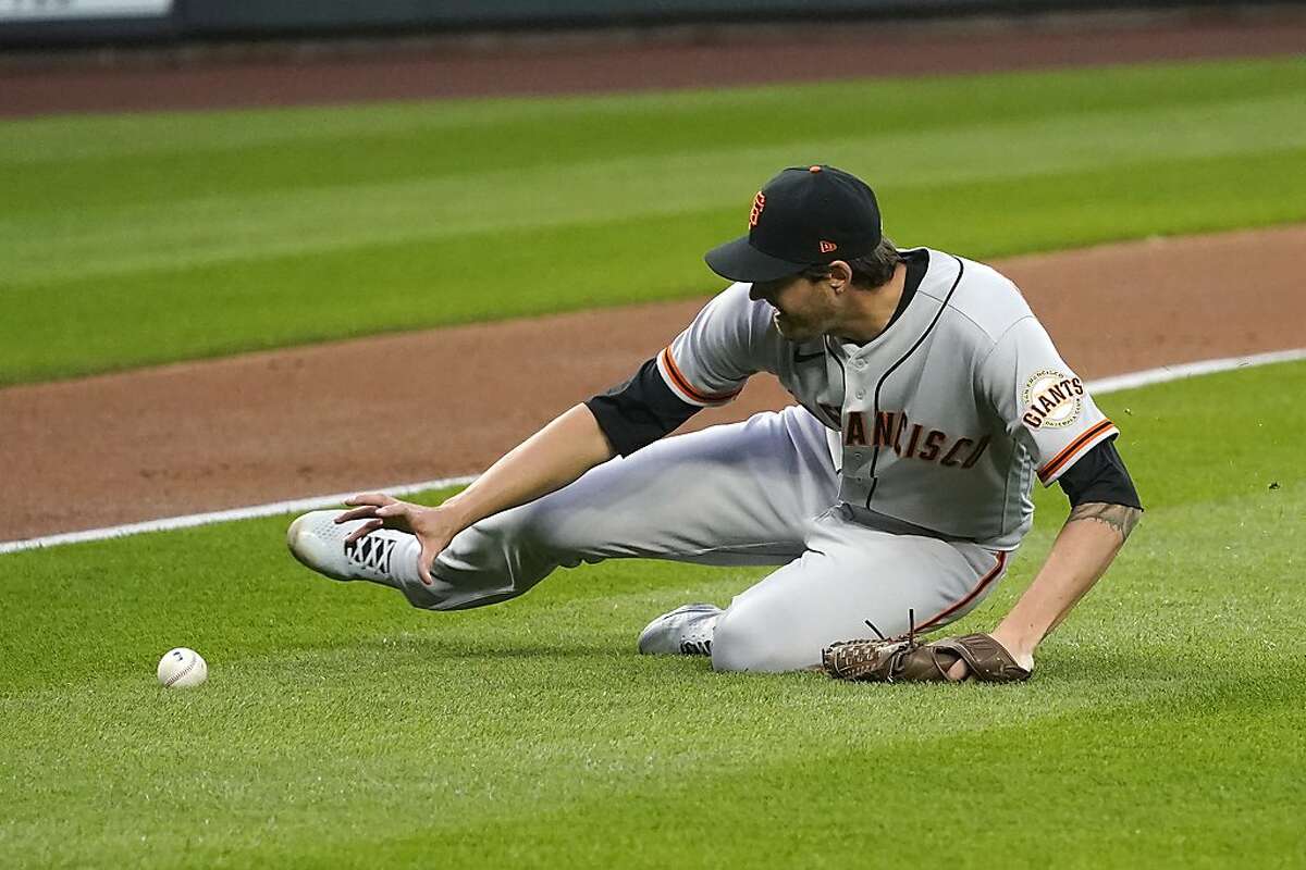 Giants starting pitcher Kevin Gausman slides across the infield to field a grounder by the Mariners’ Ty France in Thursday’s opener.