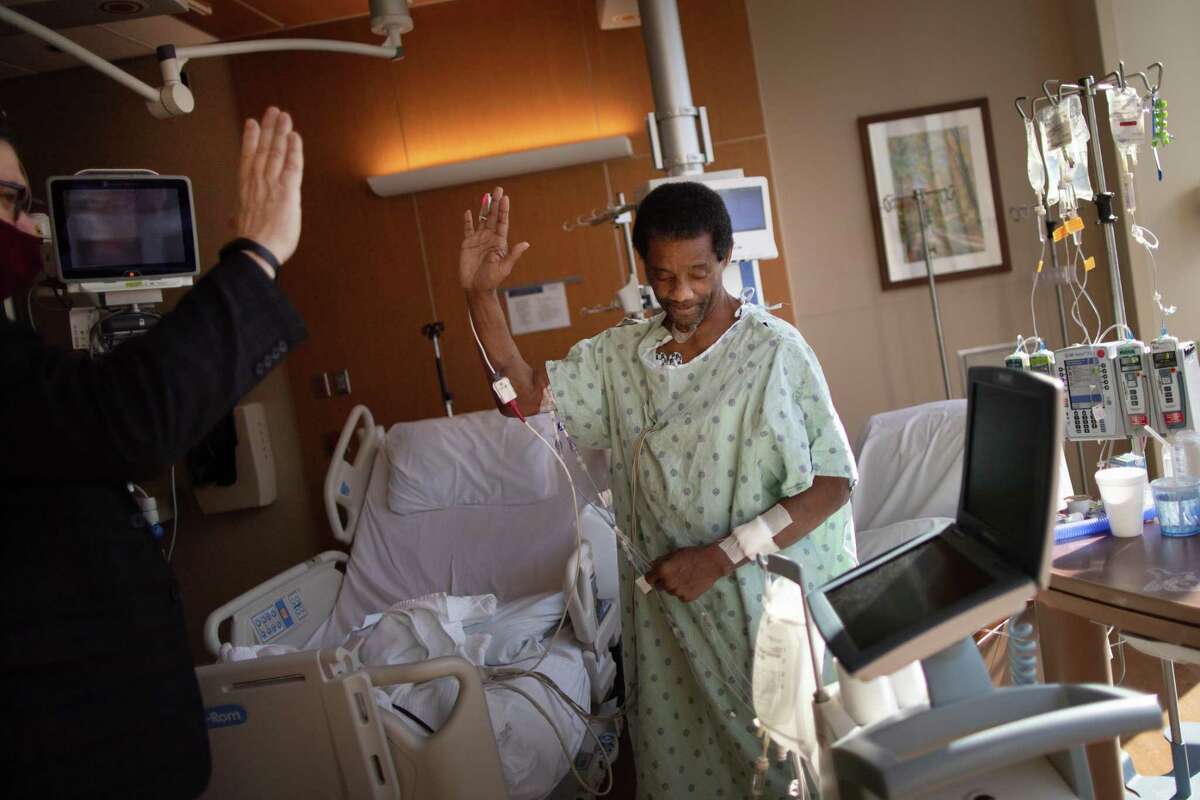 Chaplain Brian Gowan at Houston Methodist and organ transplant patient Kiven Leday, 55, gesture a high-five but without actually touching as part of precautions because of the COVID-19 pandemic, Thursday, April 1, 2021, in Houston.