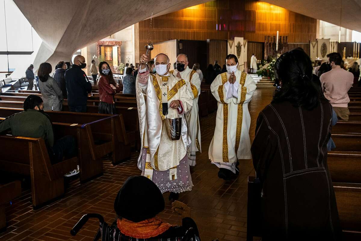 Archbishop Salvatore Cordileone sprinkles holy water onto attendees during an in-church Easter Mass.