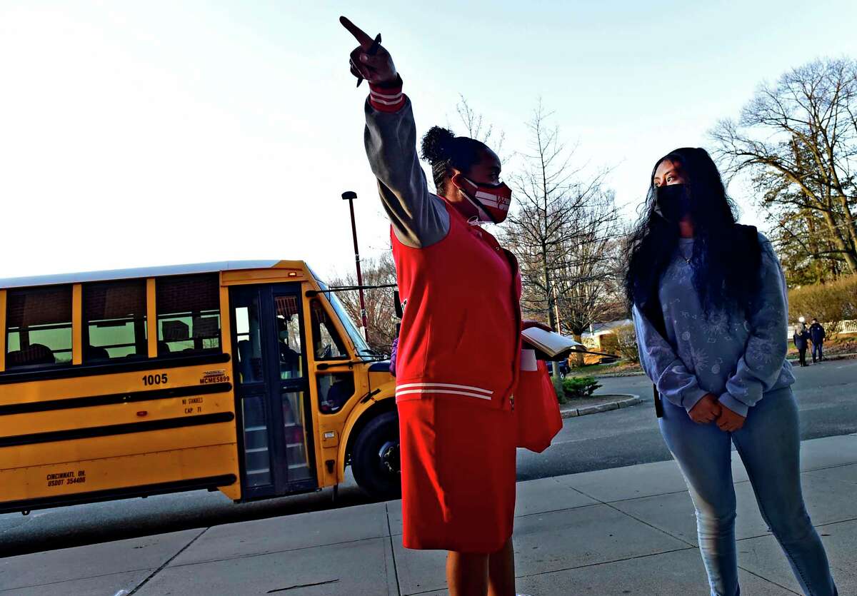 New Haven, Connecticut: Monday - April 5, 2021: Wilbur Cross H.S. principal Edith Johnson, left, greets a student at the front of the school as all New Haven High Schools reopen Monday morning with the easing of Covid-19 pandemic restrictions.