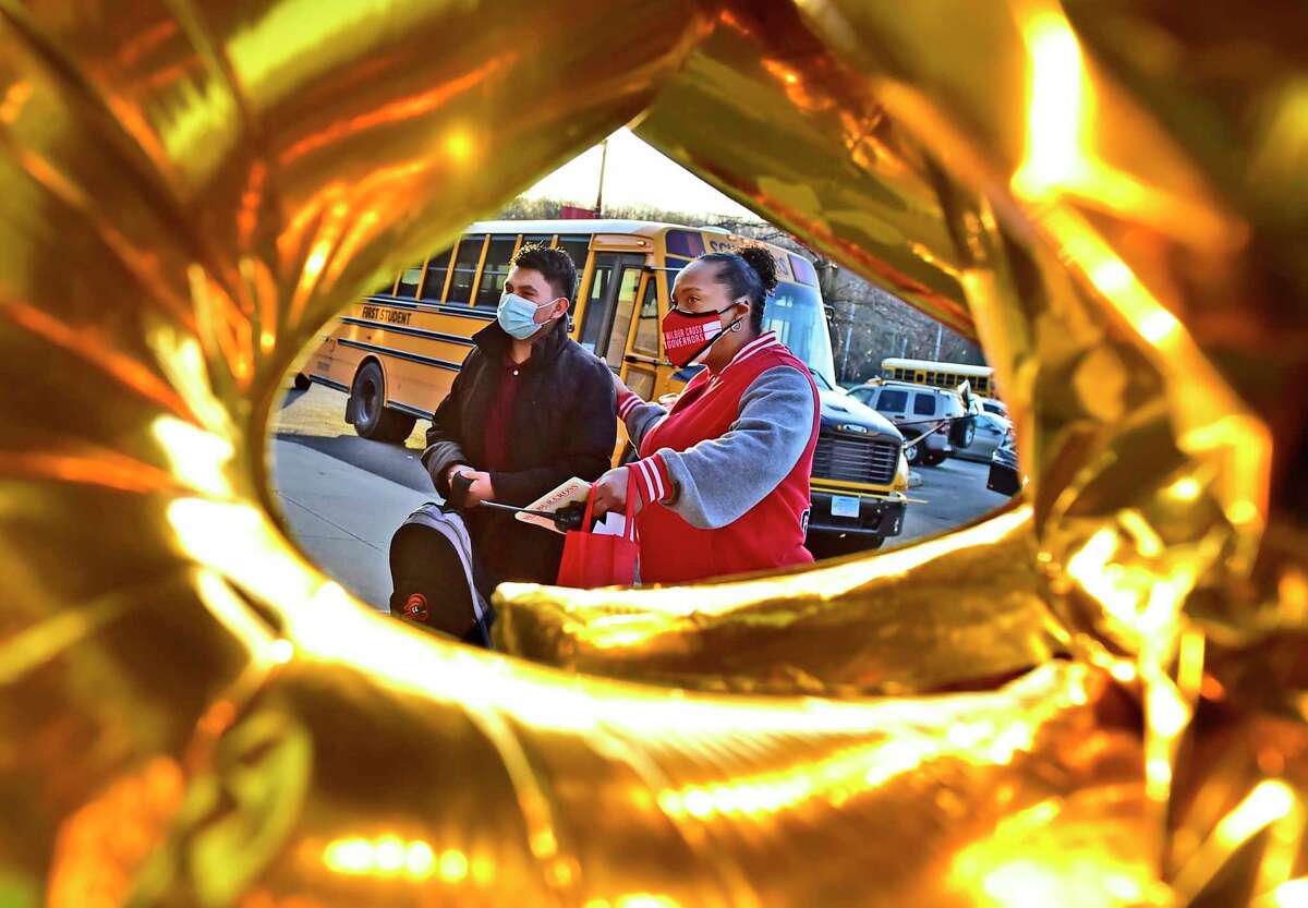 New Haven, Connecticut: Monday - April 5, 2021: Surrounded by the fanfare of ballons, Wilbur Cross H.S. principal Edith Johnson, right, greets a student at the front of the school as all New Haven High Schools reopen Monday morning with the easing of Covid-19 pandemic restrictions.