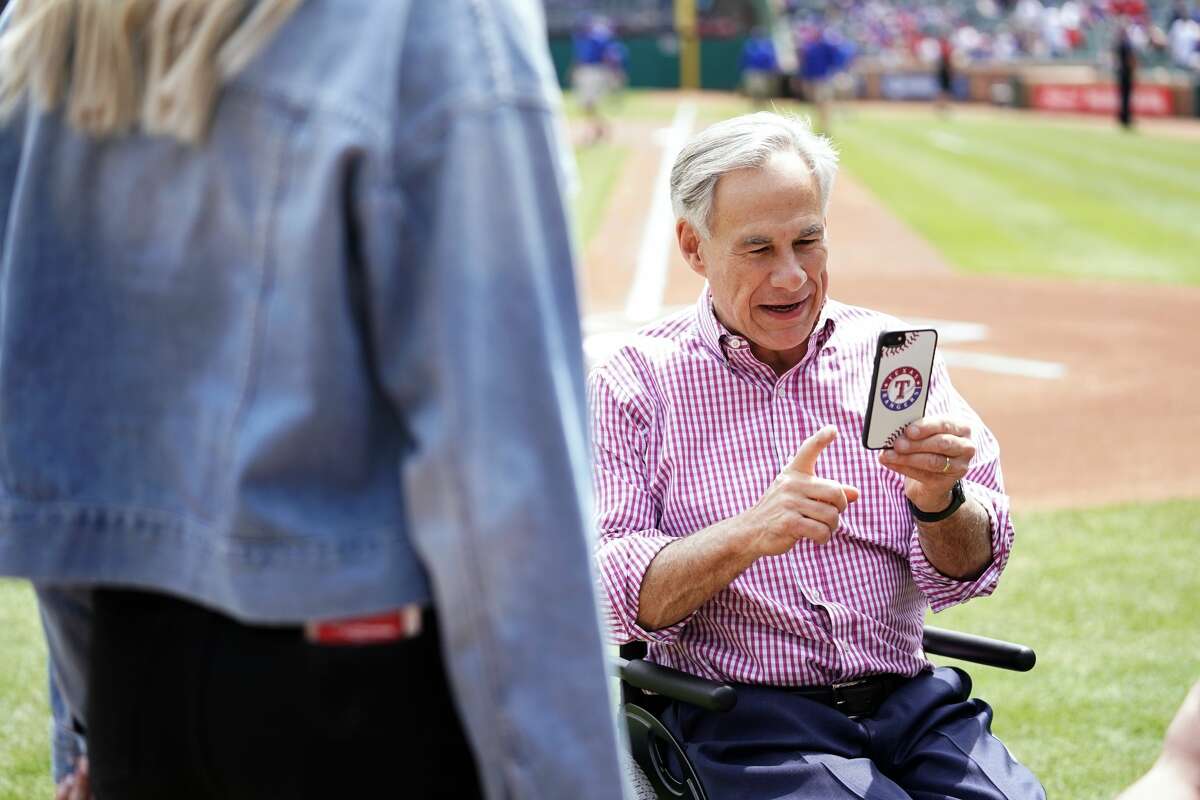 ARLINGTON, TX - MARCH 28: Texas Governor Greg Abbott uses his phone before the game between the Chicago Cubs and the Texas Rangers at Globe Life Park in Arlington on Thursday, March 28, 2019 in Arlington, Texas. (Photo by Cooper Neill/MLB via Getty Images)