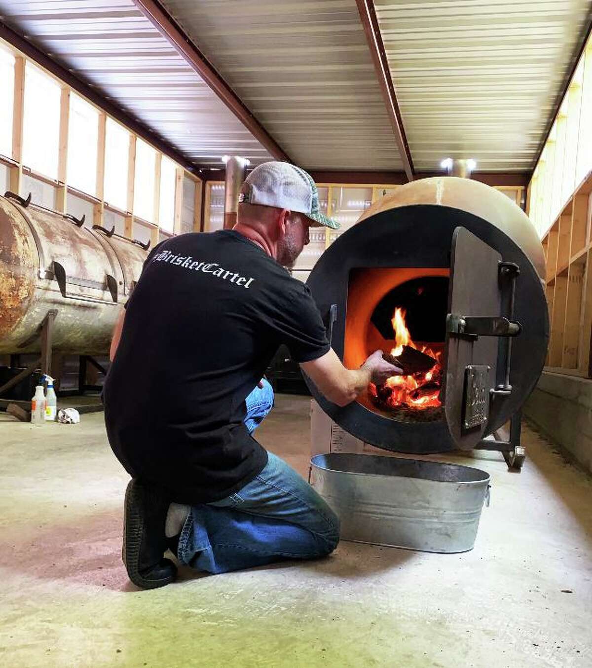 David Kirkland of the Burnt Bean Co. in Sequin feeds the fire to one of his smoker.