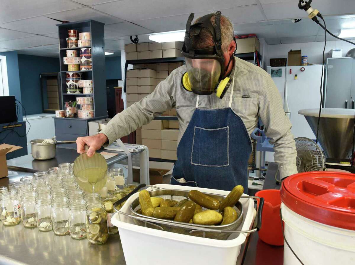 Owner Tim Bibens wears a gas mask as he adds pickling brine to glass jars as he makes pickles in the production area of Whalen's Horseradish Products on Tuesday, March 30, 2021 in Galway, N.Y. (Lori Van Buren/Times Union)