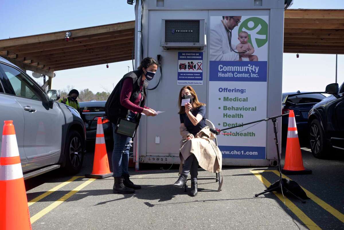 Lt. Governor Susan Bysiewicz, right, shows her vaccination card to Leonela Espinal RN before receiving her second dose of COVID_19 vaccine at the Community Health Center's mass vaccination clinic at the Danbury Fair mall. Monday, April 5, 2021, in Danbury, Conn.
