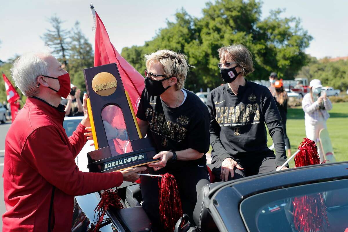 Stanford President Marc Tessier-Lavigne hands the NCAA trophy back to Kate Paye, assistant coach, at center, and Tara VanDerveer, head coach, as the Stanford women’s basketball team celebrates their NCAA Basketball Championship win with a parade at Stanford University on Monday, April 5, 2021, in Stanford, Calif.