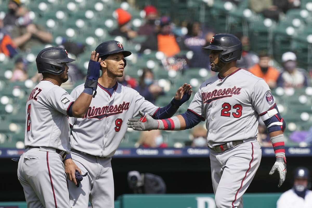 Minnesota Twins designated hitter Nelson Cruz (23) is greeted by Luis Arraez, left, and Andrelton Simmons after his grand slam during the second inning of a baseball game against the Detroit Tigers, Monday, April 5, 2021, in Detroit. (AP Photo/Carlos Osorio)