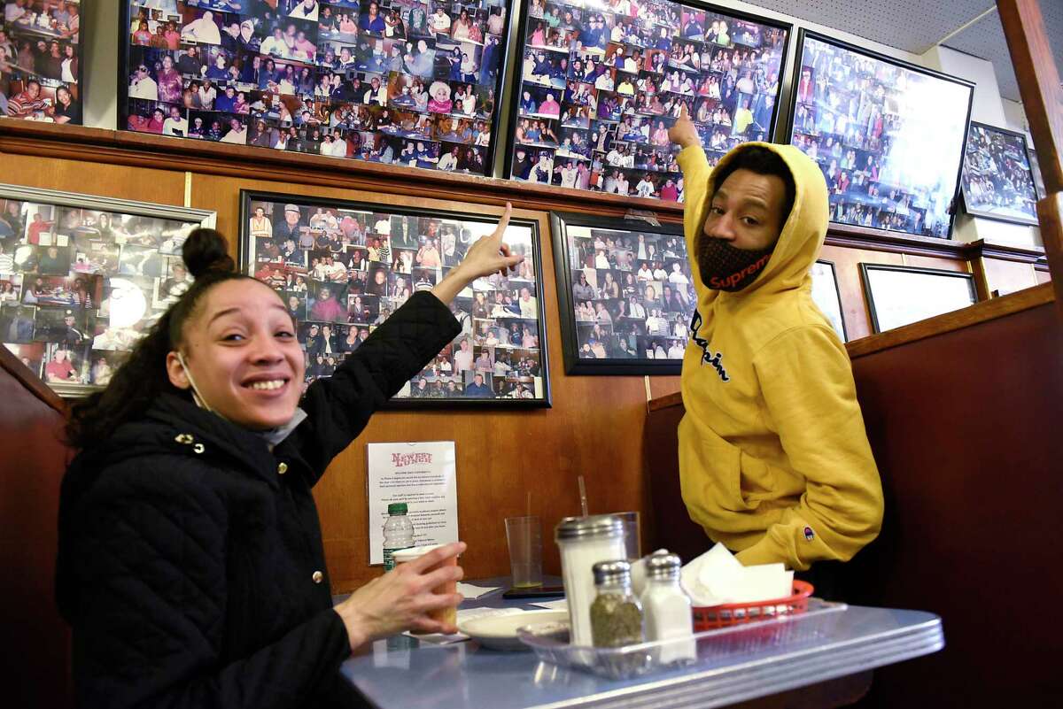Eyvonntae Washington and her husband Cory Spencer, who have been customers since they were children, point out a photo of Eyvonntae as they sit in a booth in Newest Lunch on Wednesday, March 31, 2021 in Schenectady, N.Y. The Iconic lunch spot is turning 100. (Lori Van Buren/Times Union)