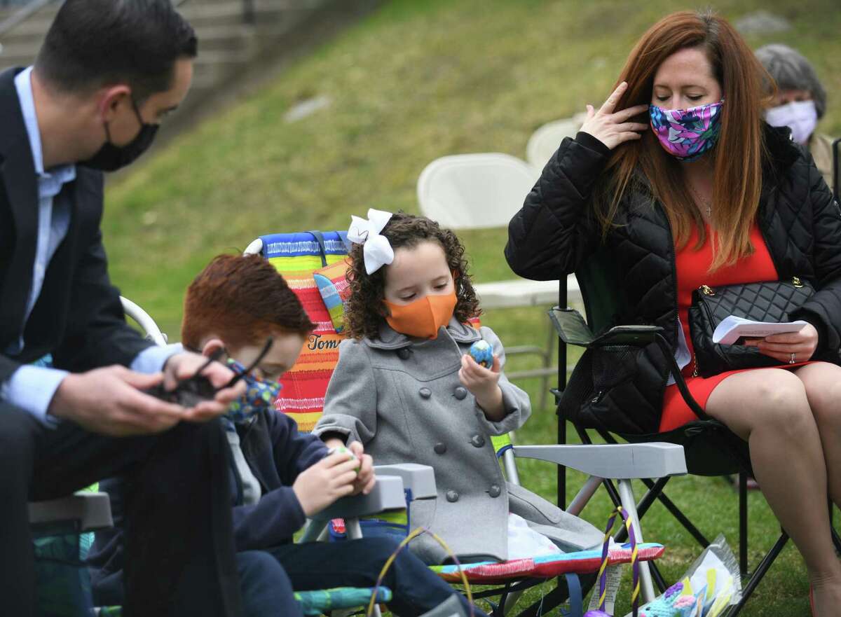 Stamford’s Joseph and Abigail Nardi, 7, and 4, look through their Easter baskets with their parents, Matthew and Annie Nardi, at the First Congregational Church Easter Sunday outdoor service at First United Methodist Church of Stamford in Stamford on Sunday. Congregants gathered outdoors to worship and sing hymns on Easter Sunday in celebration of the resurrection of Jesus.