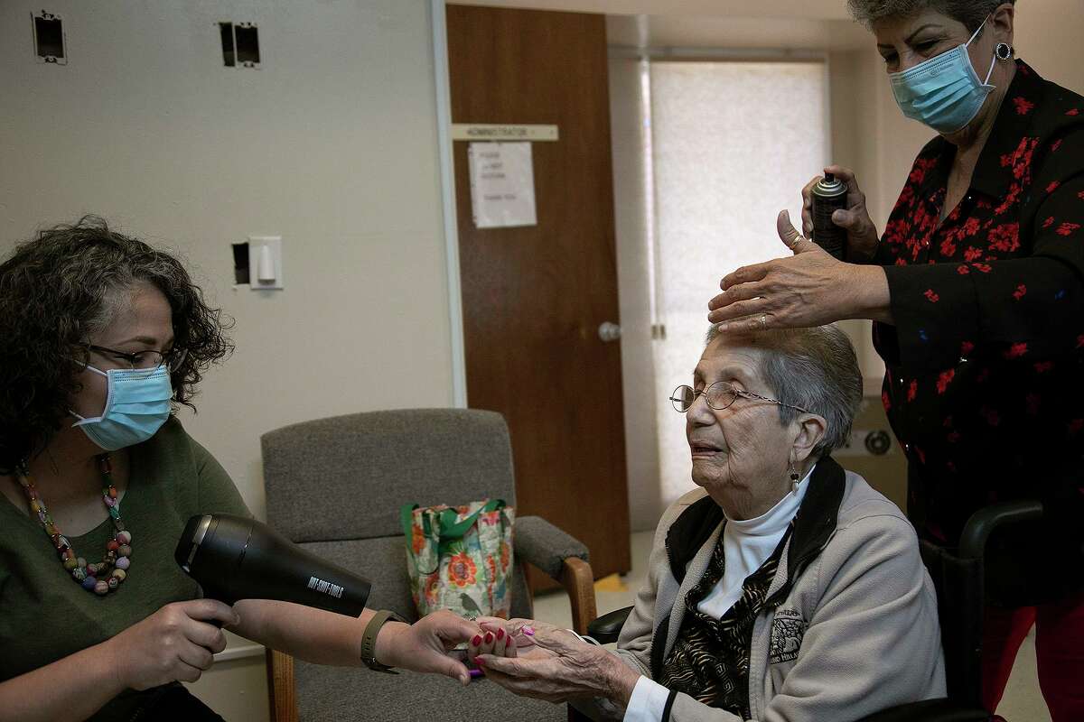 Lori Rodriguez-Padilla, left, uses a hair dryer to warm the hands of her grandmother, Mary Moreno, who said her hands were cold, while Lori's mother, does her hair.