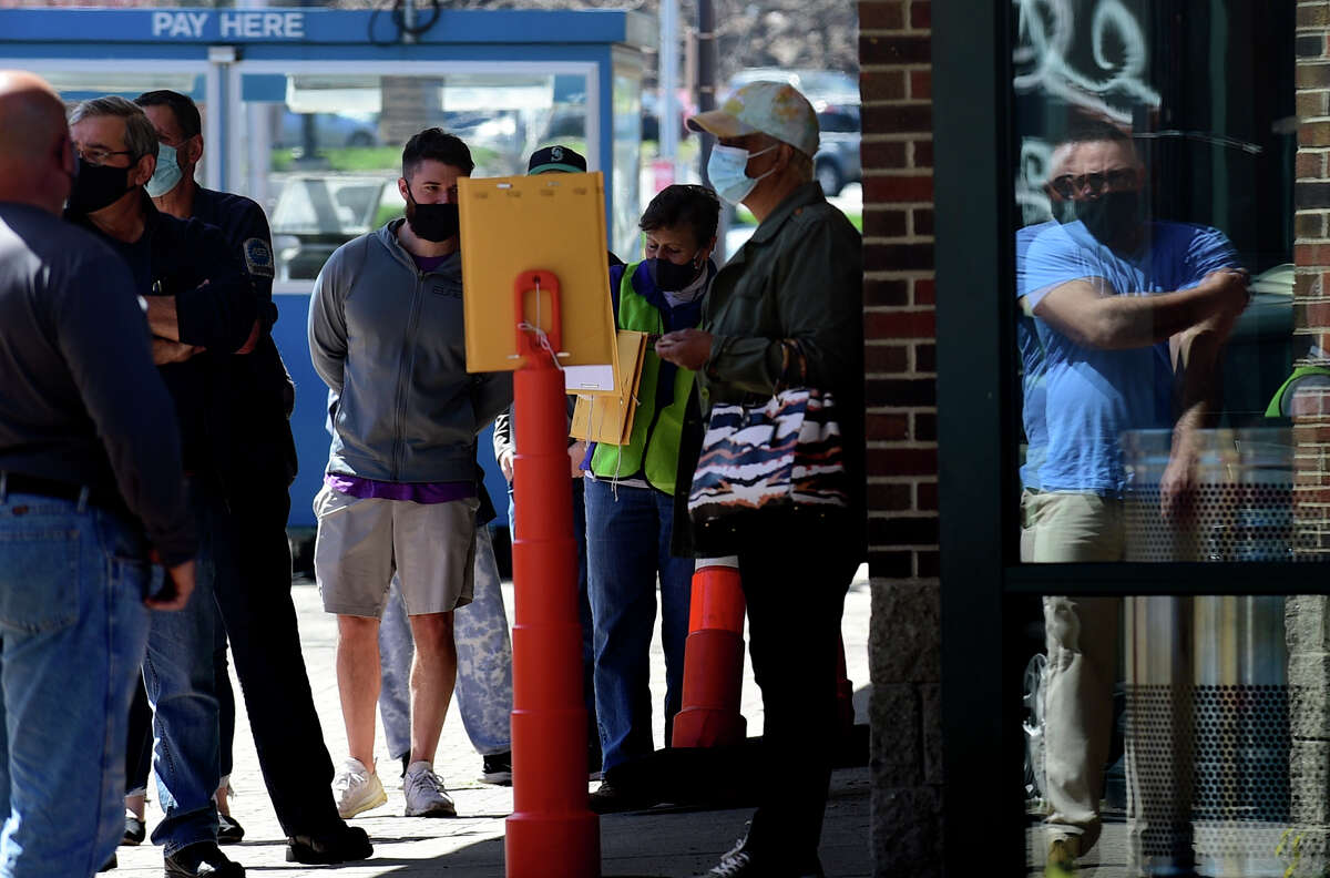 Local residents line up at the Ultimate Regent 8 movie theater where the Norwalk Health Department held a mass COVID vaccination clinic in the theater lobby Wednesday, April 7, 2021, in Norwalk, Conn. The Bow Tie Cinemas theater owner partnered with the healtth department to host the public COVID vaccination clinic.