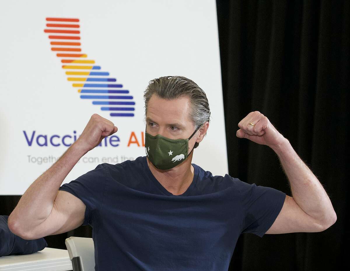 California Gov. Gavin Newsom reacts after being inoculated by Dr. Mark Ghaly, secretary of California Health and Human Services at the Baldwin Hills Crenshaw Plaza in Los Angeles Thursday, April 1, 2021.