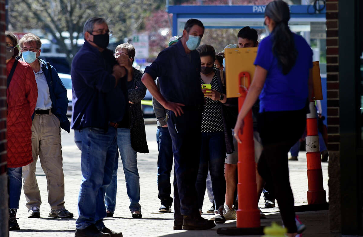 Local residents line up at the Ultimate Regent 8 movie theater where the Norwalk Health Department held a mass COVID vaccination clinic in the theater lobby Wednesday, April 7, 2021, in Norwalk, Conn. The Bow Tie Cinemas theater owner partnered with the healtth department to host the public COVID vaccination clinic.