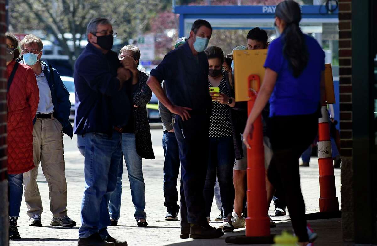 Local residents line up at the Ultimate Regent 8 movie theater where the Norwalk Health Department held a mass COVID vaccination clinic in the theater lobby Wednesday, April 7, 2021, in Norwalk, Conn. The Bow Tie Cinemas theater owner partnered with the healtth department to host the public COVID vaccination clinic.
