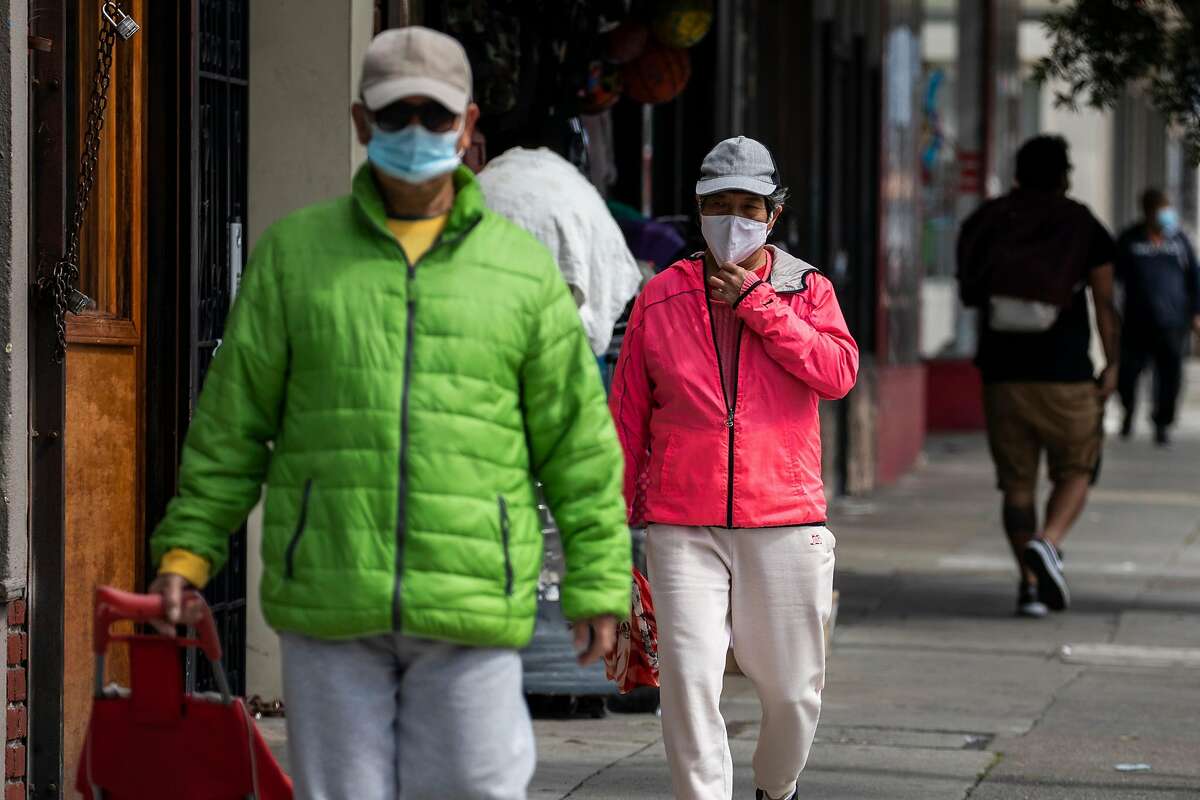 Masked pedestrians walk along Mission Street in the Excelsior district of San Francisco on April 7, 2021.