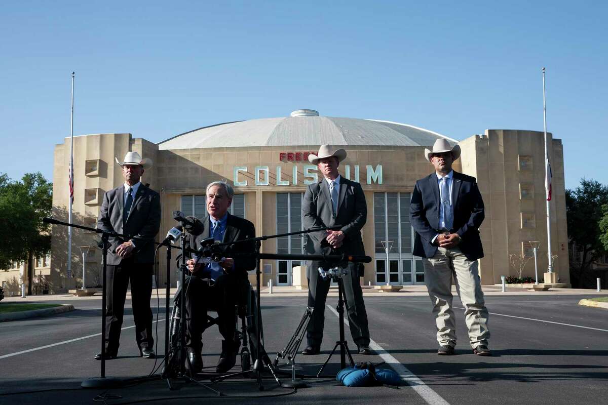 Flanked by Texas Rangers, Gov. Greg Abbott speaks Wednesday in front of the Freeman Coliseum, where a temporary facility has been set up to house unaccompanied migrant minor boys. The governor called on the federal government to shut down the facility, saying two state agencies had received complaints Wednesday morning alleging child abuse and neglect.