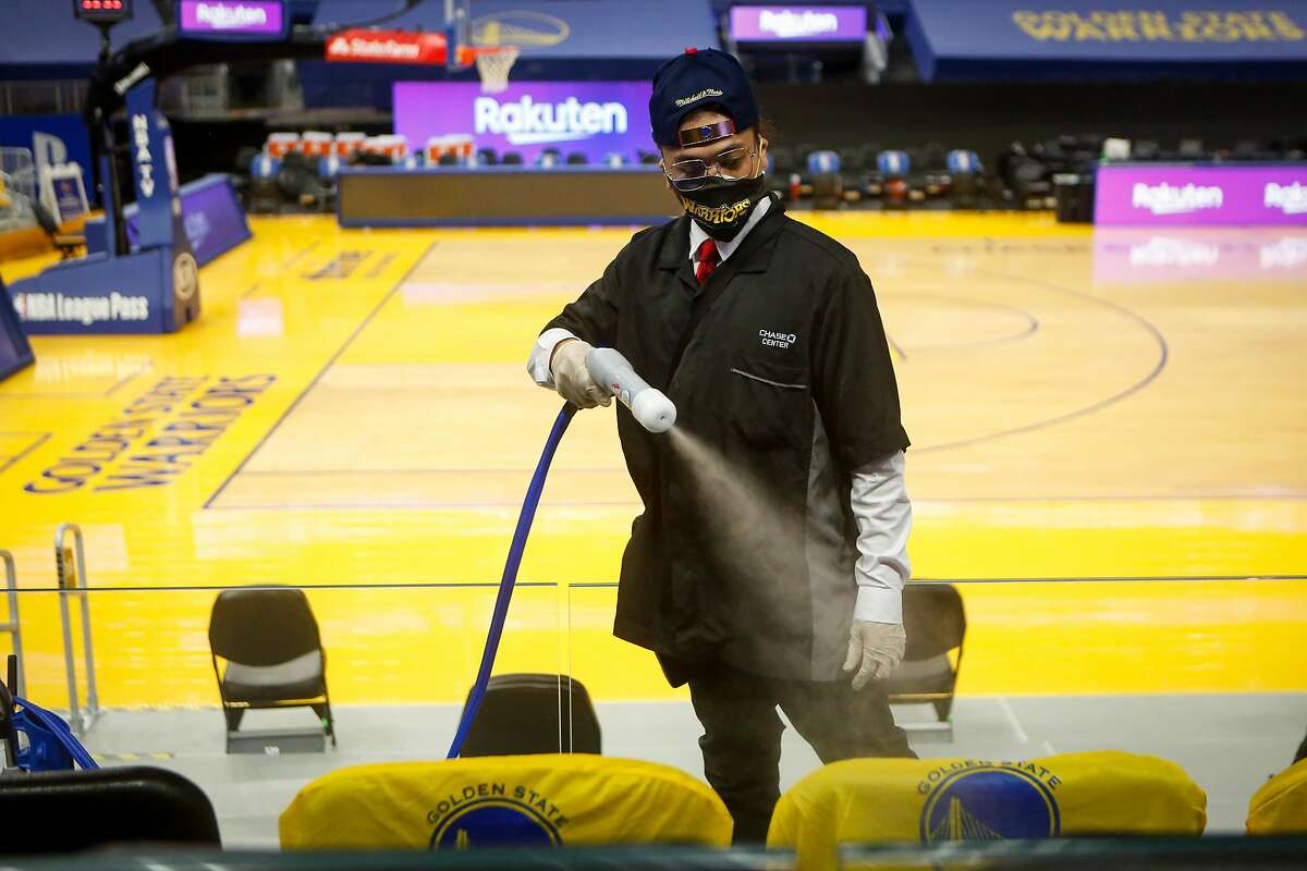 Ryan Tirazona uses an electrostatic sprayer this month to disinfect seats as Chase Center prepares to reopen soon.