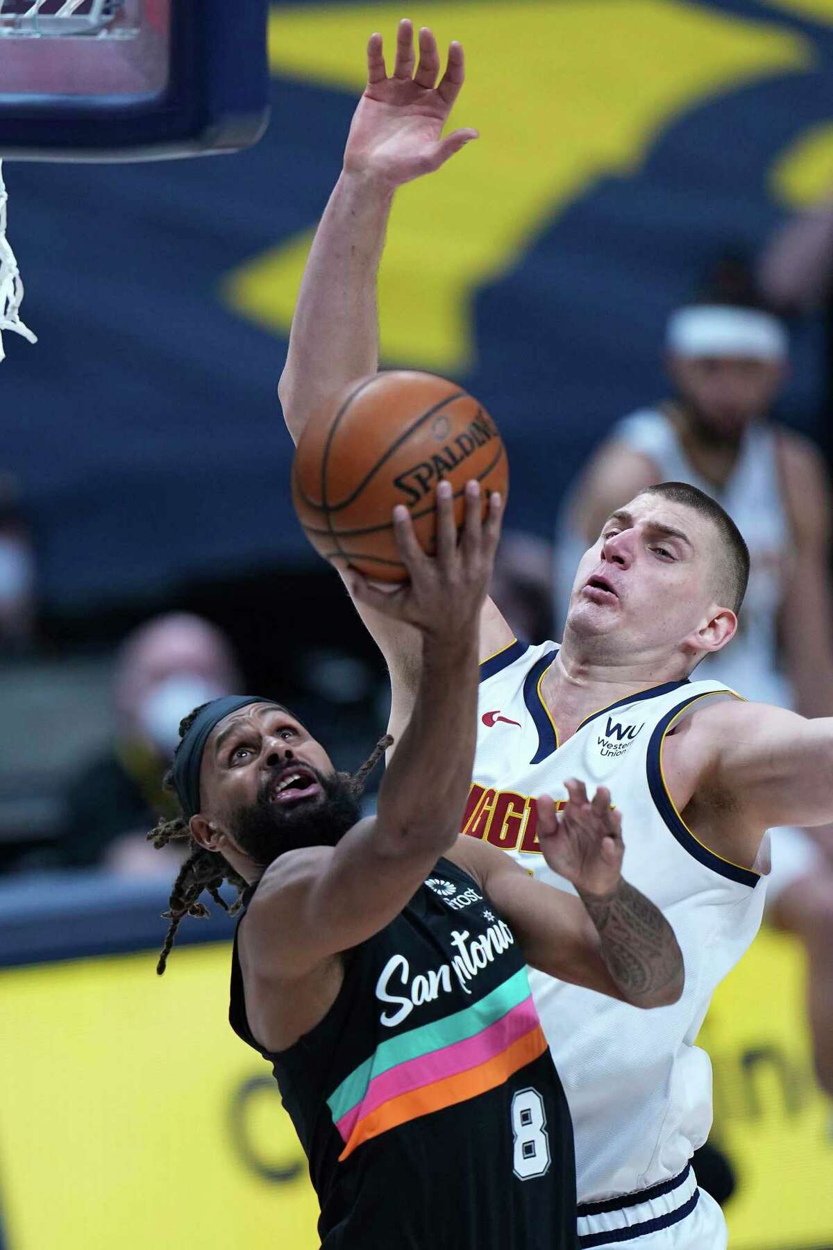 San Antonio Spurs guard Patty Mills (8) shoots against Denver Nuggets center Nikola Jokic during the first quarter of an NBA basketball game Wednesday, April 7, 2021, in Denver. (AP Photo/Jack Dempsey)