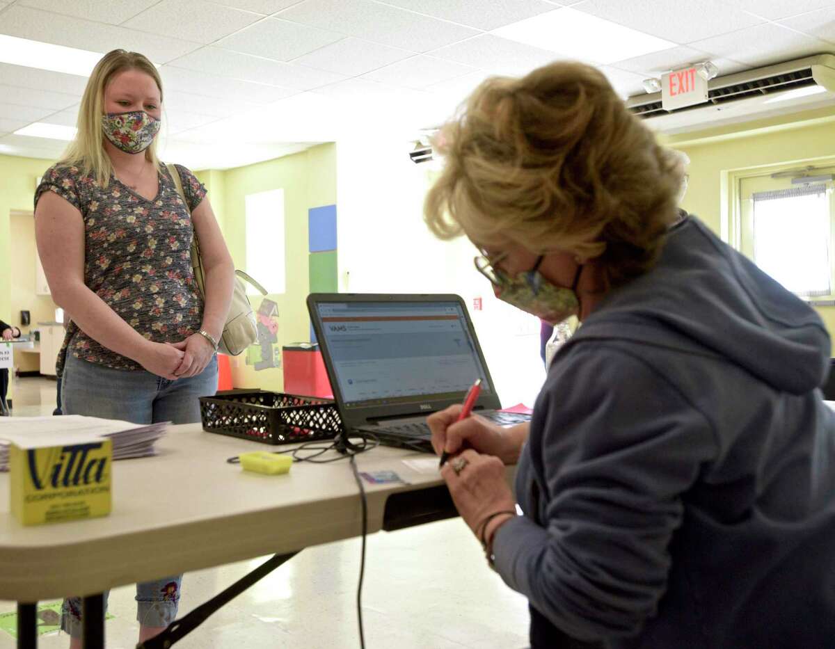 Jennifer Barabas, of Brookfield, is checked in at the new Brookfield clinic by volunteer Margaret Unfried, of Danbury, to received her first dose of COVID-19 vaccine. The clinic is now at the old St Joseph Catholic Academy. Wednesday, April 8, 2021, in Brookfield, Conn.