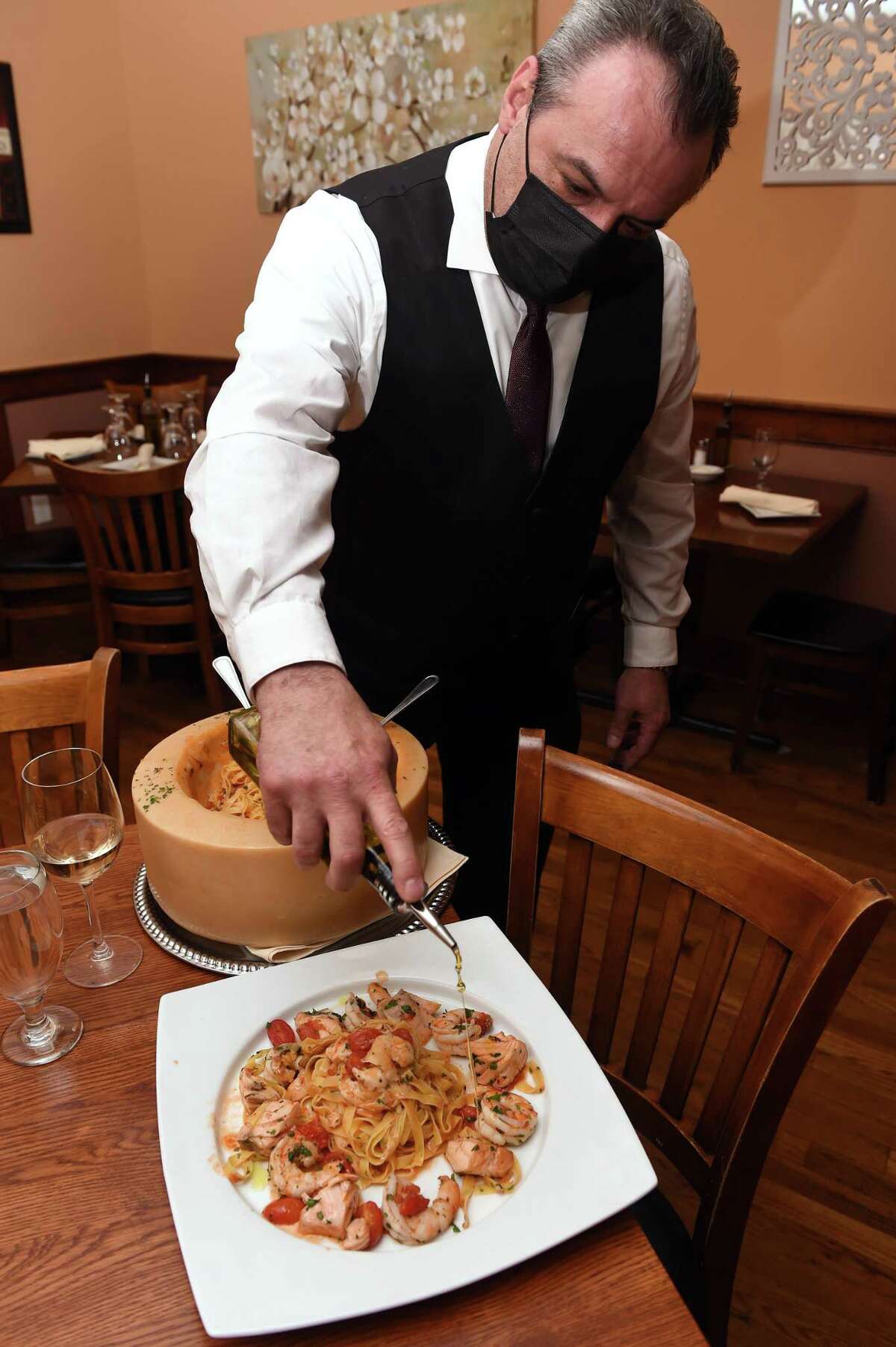 Adriana's Restaurant and Wine Bar manager Adrian Gjonbalaj finishes an entree of fettuccine with salmon, shrimp, cherry tomatoes and garlic and a touch of olive oil, prepared in a hollowed-out Parmesan cheese wheel.