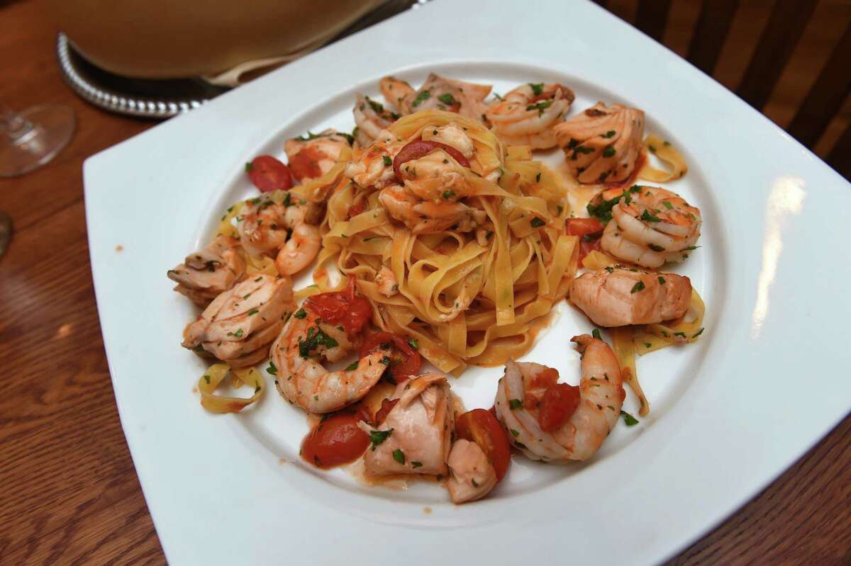 An entree of fettuccine with salmon, shrimp, cherry tomatoes and garlic and a touch of olive oil, prepared in a hollowed-out Parmesan cheese wheel at Adriana's Restaurant and Wine Bar in New Haven.