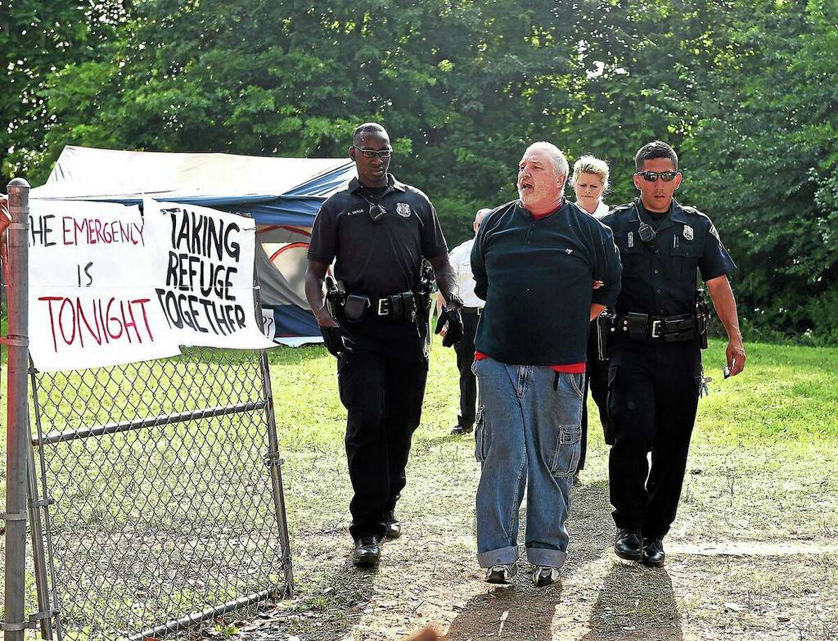 In this file photo, New Haven Police arrest Mark Colville of the Amistad Catholic Worker House at 634 Howard Avenue, a city owned property, a day after the group erected a homeless tent compound in 2014.
