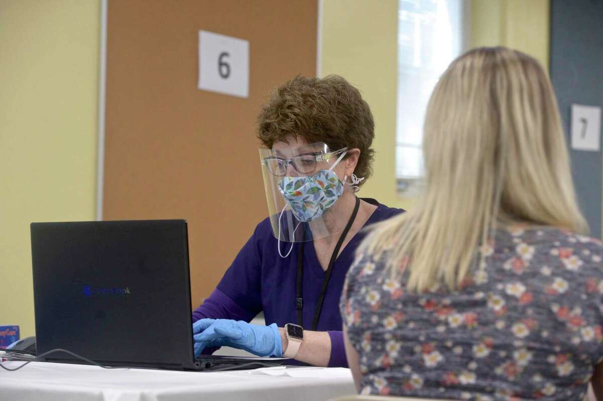 Jennifer Barabas, of Brookfield, has her information taken down by pharmacist Kathy Haddy before she receives her first dose of COVID-19 vaccine at the new location of the Brookfield clinic. The clinic is set up in the old St Joseph Catholic Academy. Wednesday, April 8, 2021, in Brookfield, Conn.