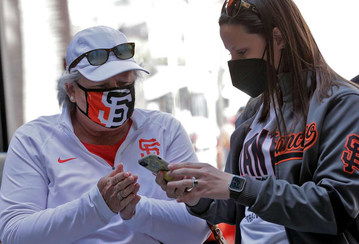 Morgan Matthews, right, helps her mom, Kim Peters, both from Fresno, navigate the new entrance apps on her phone as fans enter the ballpark before the San Francisco Giants played the Colorado Rockies at Oracle Park in San Francisco Calif., on Friday, April 9, 2021.