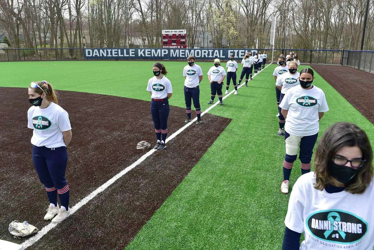 Milford, Connecticut -Saturday- April 10, 2021: Softball players stand for a moment of silence for Foran H.S. softball player Danielle “Danni” Kemp, who lost her battle with cancer at 19, during the dedication of the Foran High School Danielle Kemp Memorial Field on the opening day of high school spring sports Saturday before the Jonathon Law H.S. vs. Foran H.S. softball game.