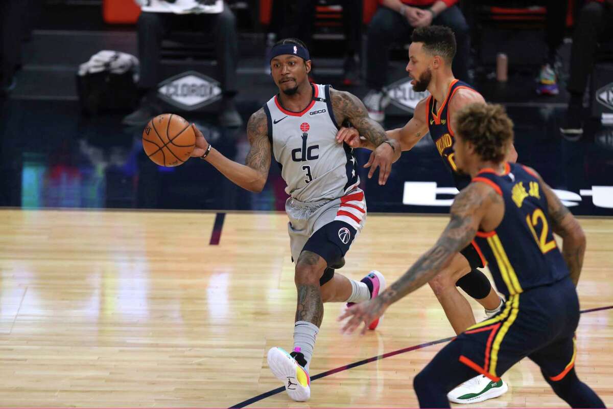 Washington Wizards forward Bradley Beal, left, passes the ball as Golden State Warriors forward Kelly Oubre Jr., front, and guard Stephen Curry, rear, defend during the first half of an NBA basketball game in San Francisco, Friday, April 9, 2021. (AP Photo/Jed Jacobsohn)