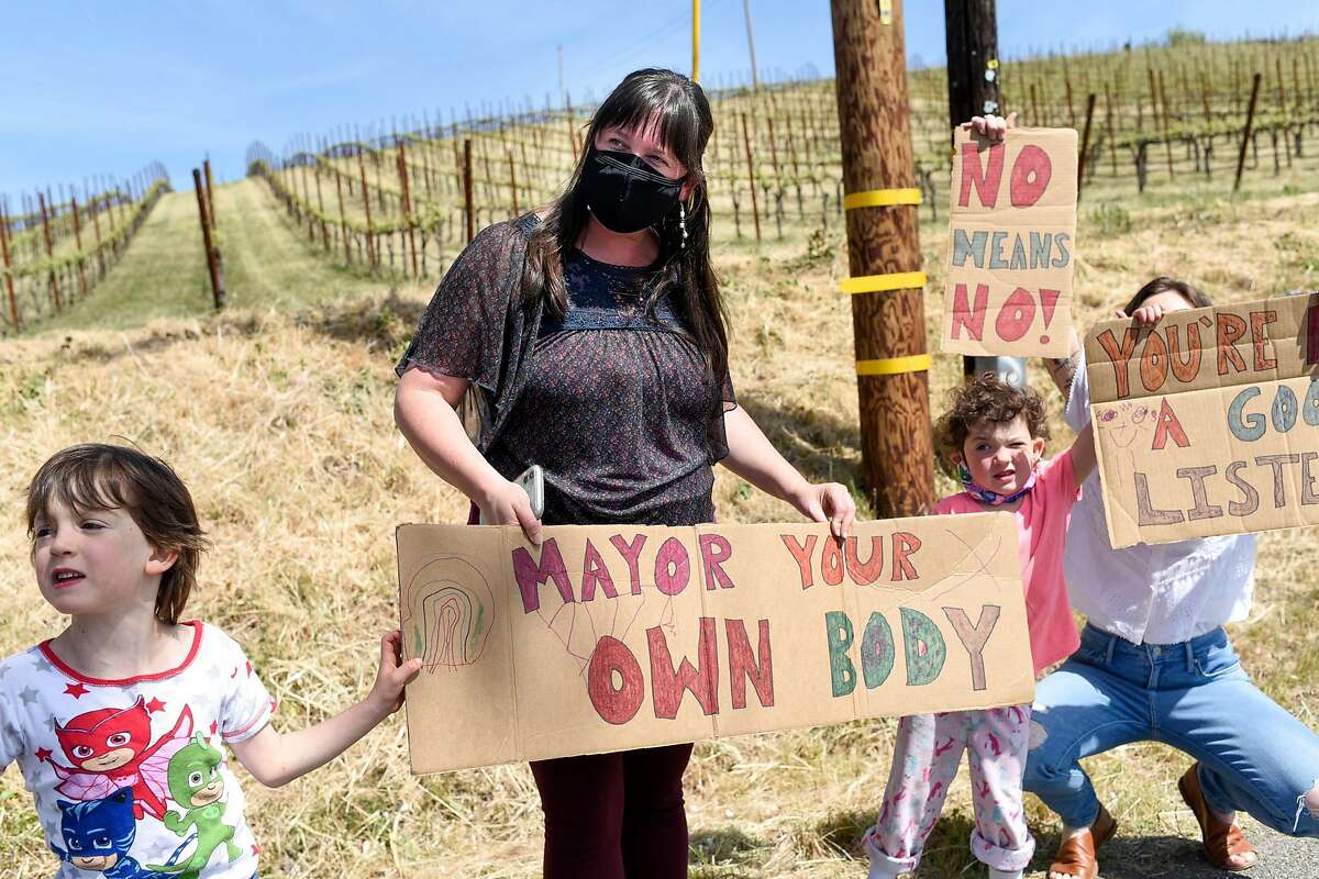 Sophia Williams (center) one of the women who came forward with allegations of sexual assault against Windsor Mayor Dominic Foppoli, her son, Benji Henderson, 5, daughter, Gracie Henderson, 4, and her business partner, Lea Ritter, hold signs at a rally calling for Windsor Mayor Dominic Foppoli to resign outside Christopher Creek Winery in Healdsburg.