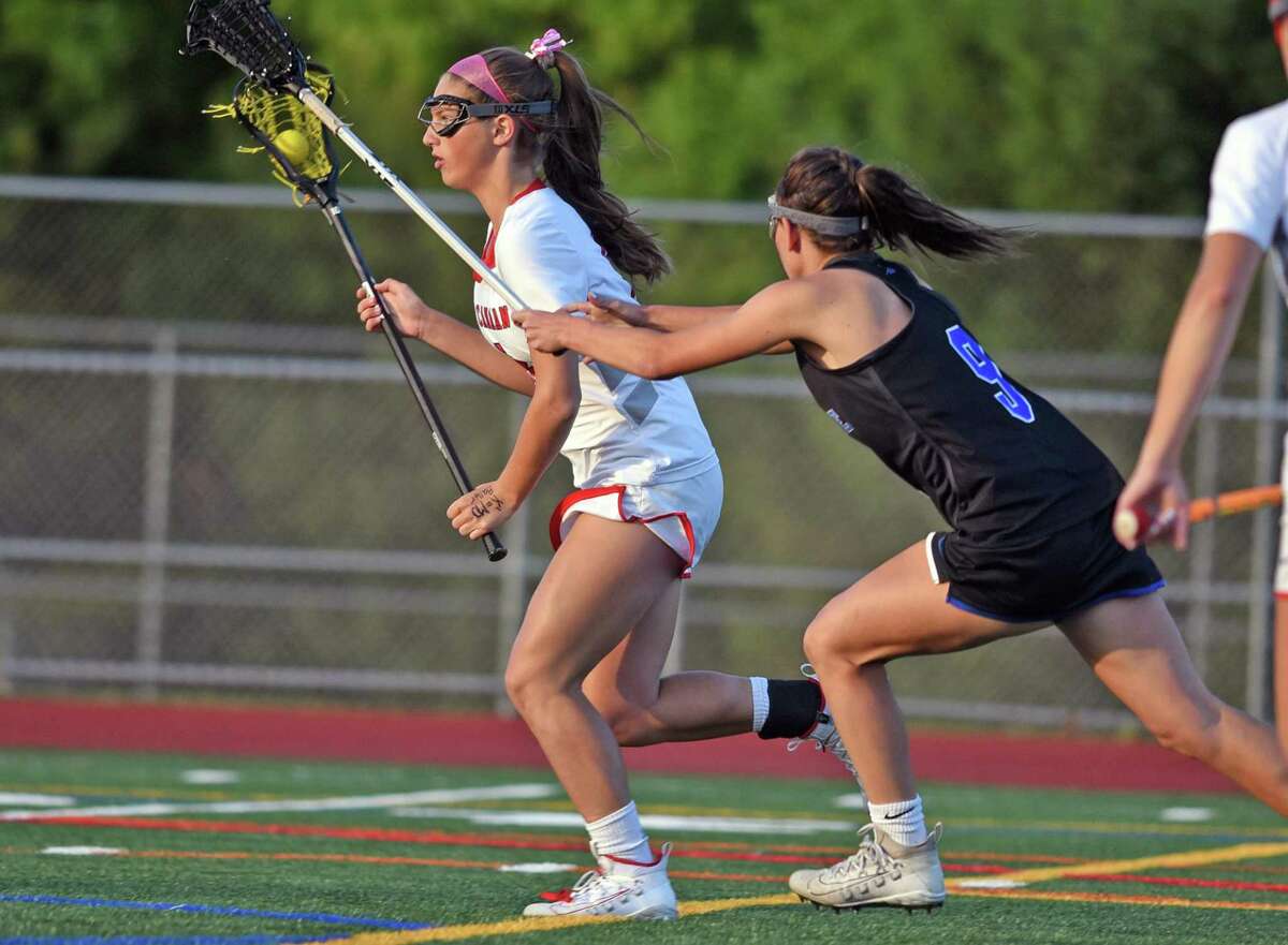 New Canaan’s McKenna Hardenl , left, charges the net as Darien’s Kate Bellissimo pursues during the FCIAC girls lacrosse championship in 2019 at Testa Field in Norwalk.