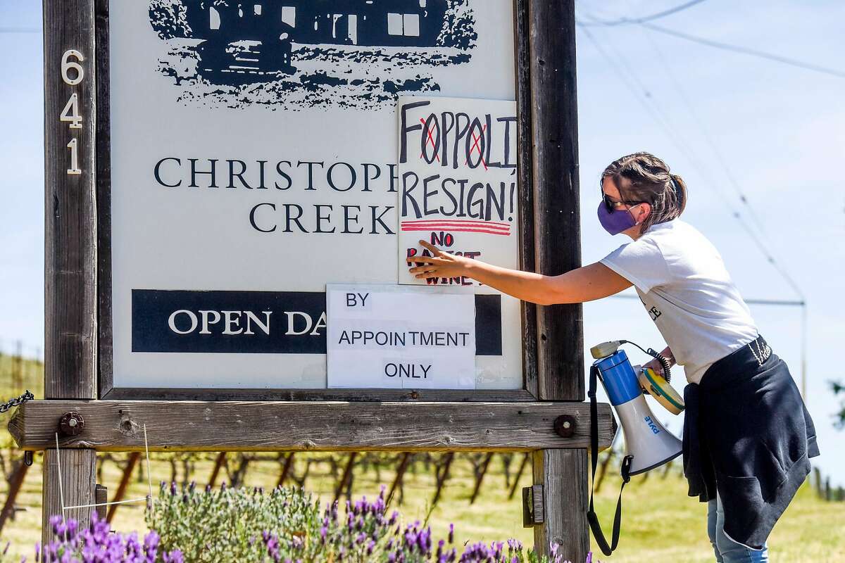 Hollie Clausen of Santa Rosa holds up a sign calling for Windsor Mayor Dominic Foppoli to resign at a rally outside Christopher Creek Winery in Healdsburg.