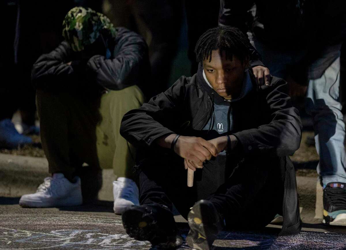 A man sits near a circle around a memorial for Daunte Wright in Brooklyn Center, Minn., Sunday, April 11, 2021. Wright's family told a crowd that he was shot by police Sunday before getting back into his car and driving away, then crashing the vehicle several blocks away. The family said Wright was later pronounced dead. (Carlos Gonzalez/Star Tribune via AP)