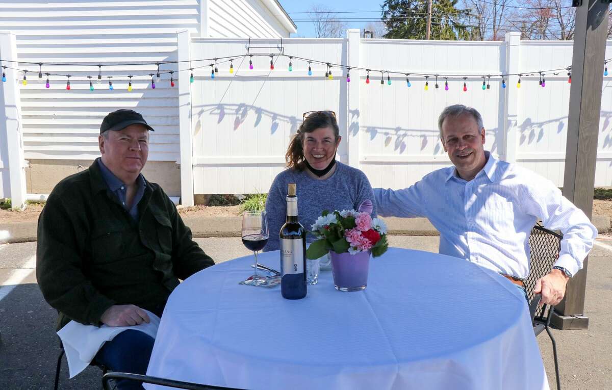 Ellen Mavuli, center, and her brother Steve Casey, right, join Len Hall at a temporary outdoor dining table at Gusto Trattoria in Milford.