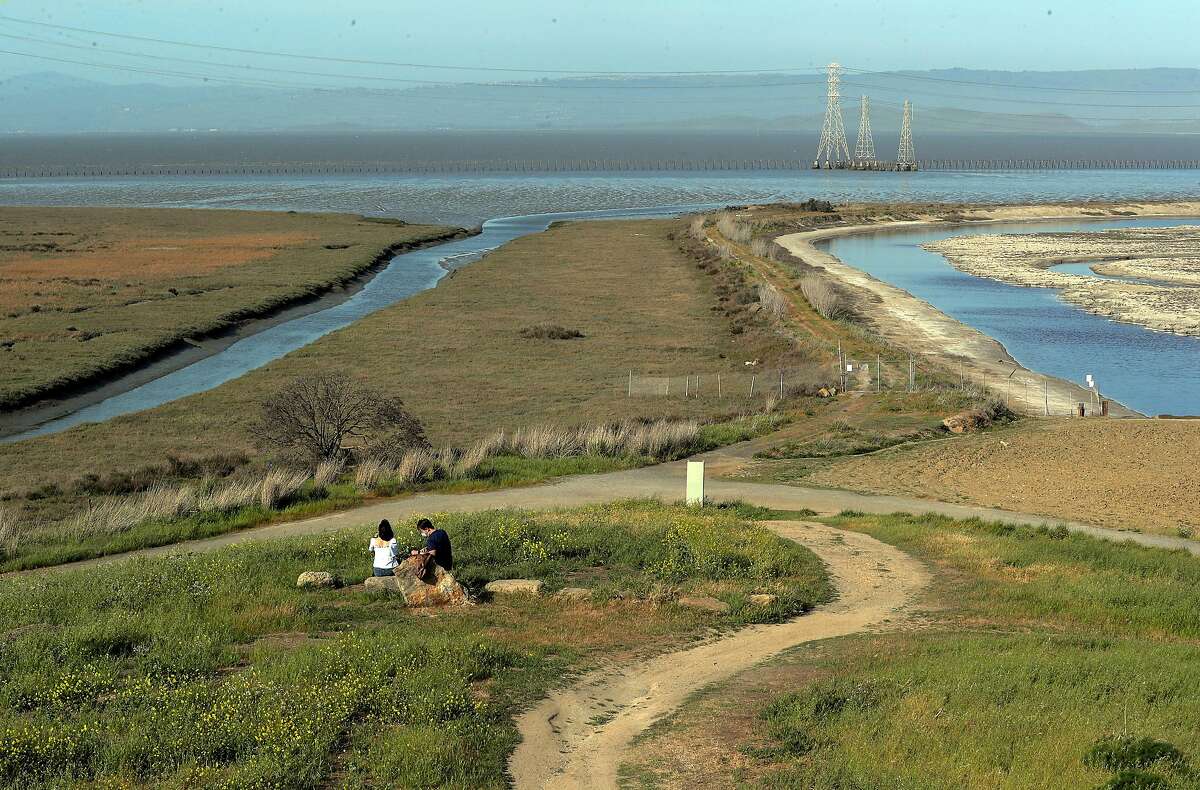 Ilyas Mailibayev his wife Alem stop for a picnic at Bedwell Bayfront Park in Menlo Park, Calif., on Sunday, April 11, 2021. The salt pond R4 on the right will be converted to a marsh like Greco Island on the left with sediment that will be dredged from the bay to help build up the area hopefully to alleviate sea level rise.