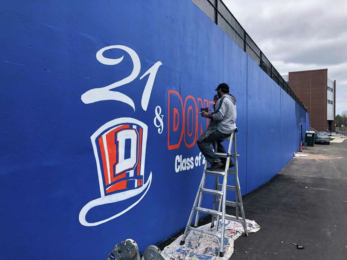 Joe Di Guiseppi, an art teacher at Westside Middle School, paints a mural honoring the Class of 2021 at Danbury High School on Saturday, April 10, 2021.