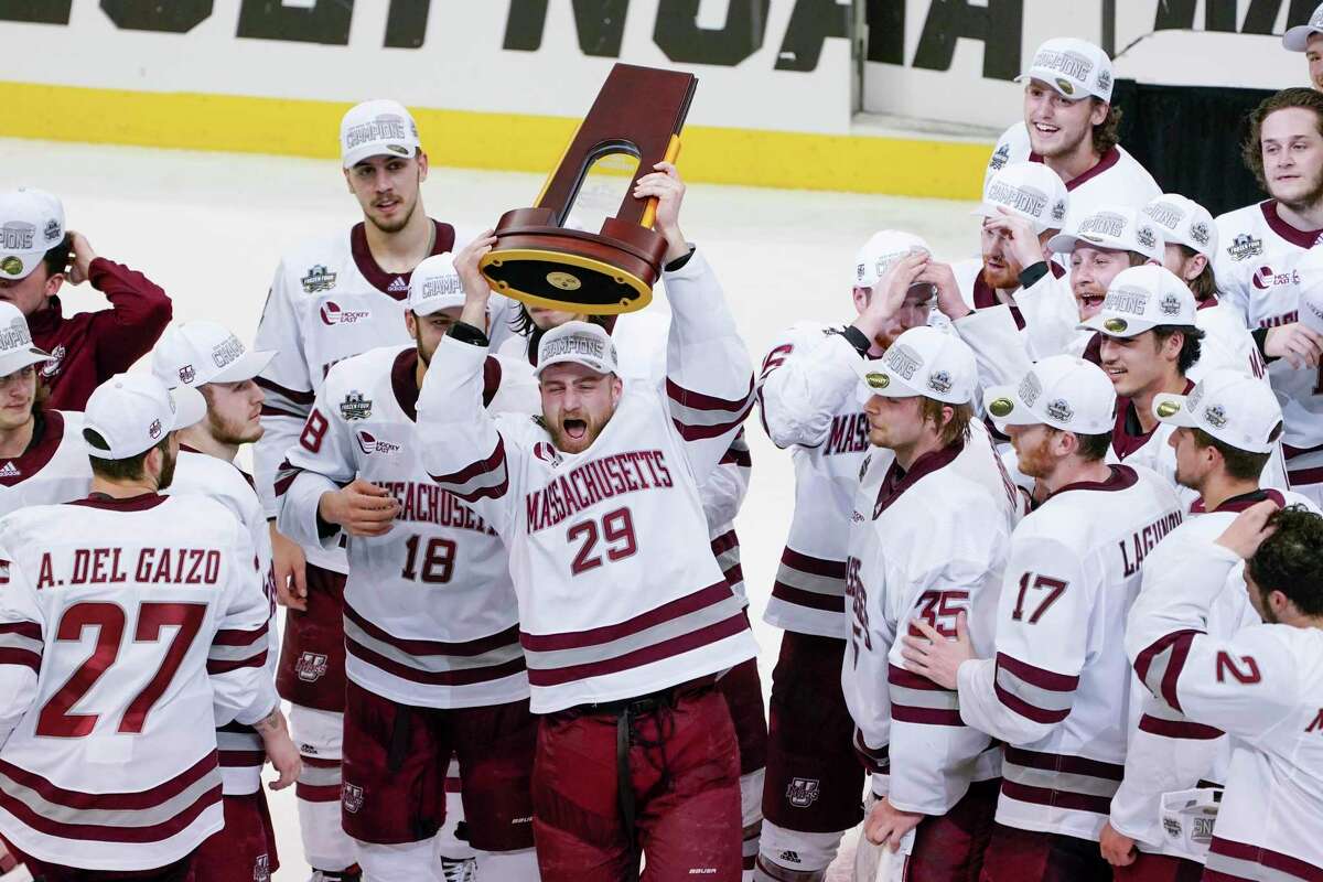 UMass’ George Mika (29) holds the NCAA trophy over his head as he skates with the team to celebrate their 5-0 win over St. Cloud State in the Frozen Four championship game Saturday.