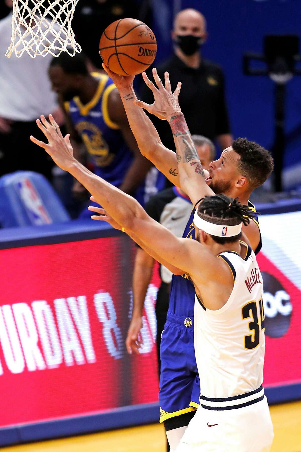 Golden State Warriors' Stephen Curry scores a basket against Denver Nuggets' JaVale McGee, passing Wilt Chamberlain for most points in franchise history, during 1st quarter of NBA game at Chase Center in San Francisco, Calif., on Monday, April 12, 2021.