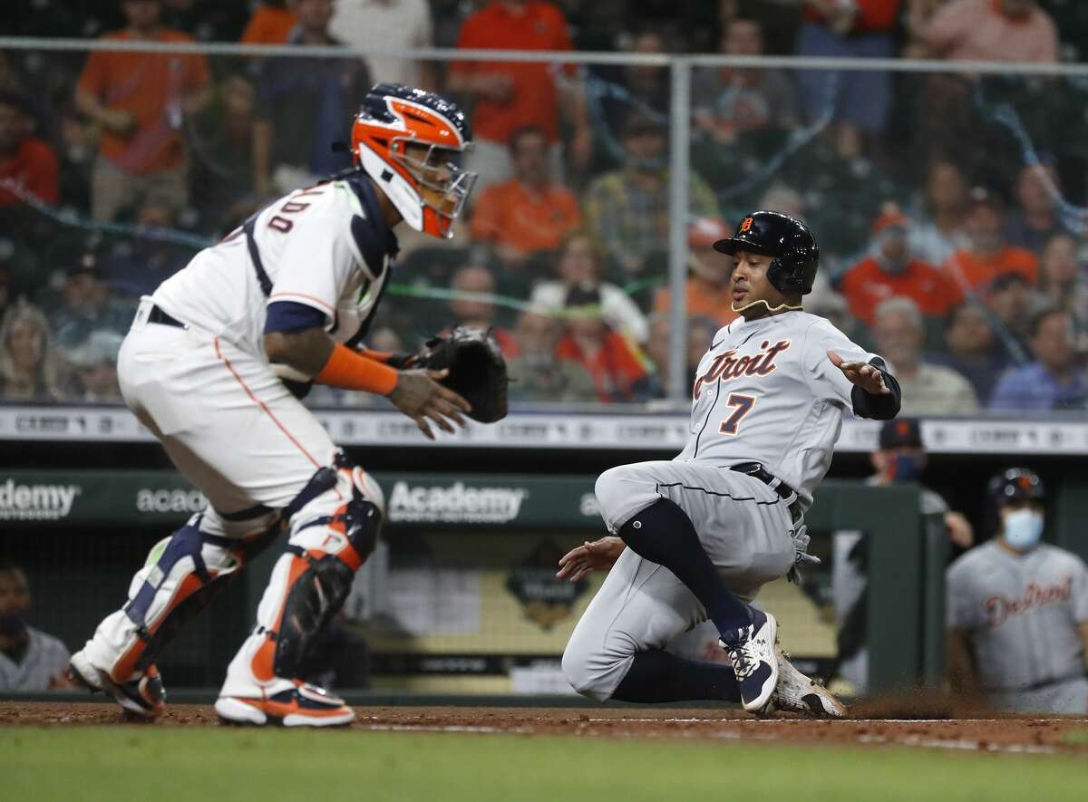 Detroit Tigers Jonathan Schoop (7) slides home to score a run on Grayson Greiner's single against Houston Astros catcher Martin Maldonado (15) during the fifth inning of an MLB baseball game at Minute Maid Park, in Houston, Monday, April 12, 2021.